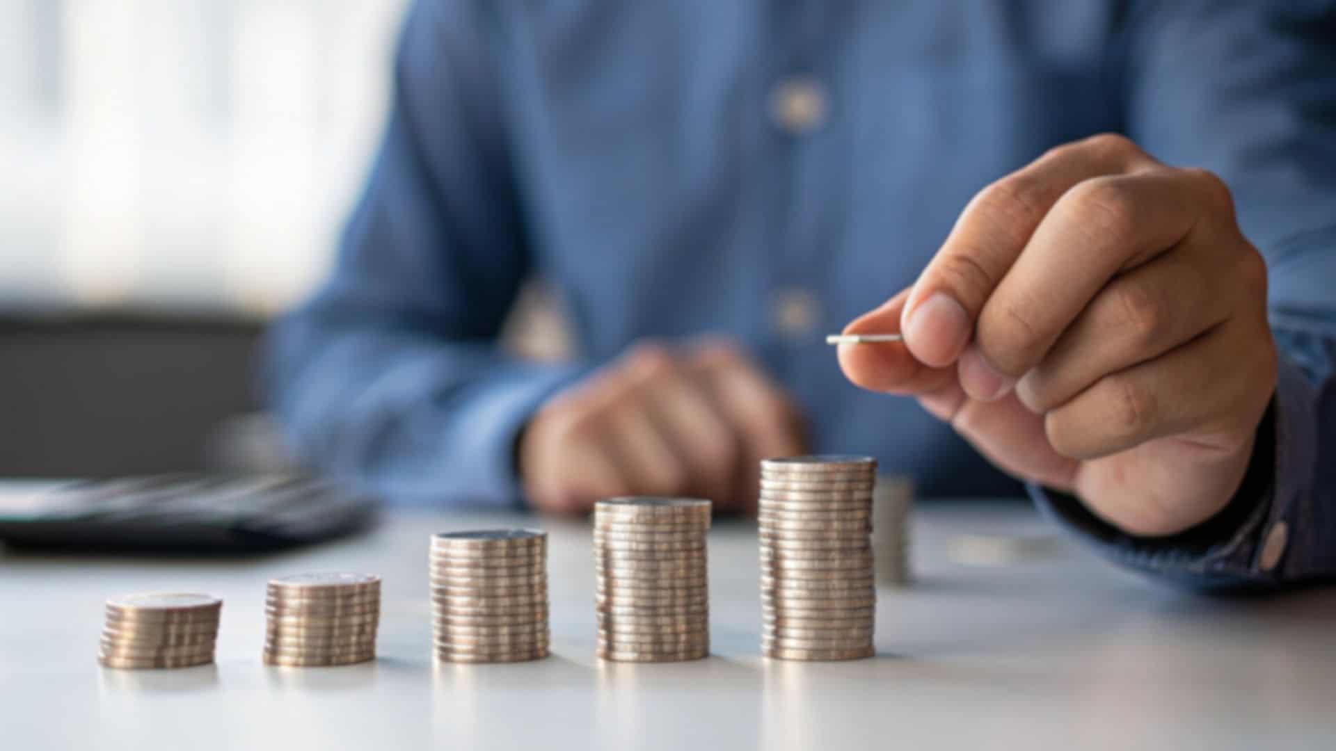 Uomo che impila monetine ordinandole in altezza crescente