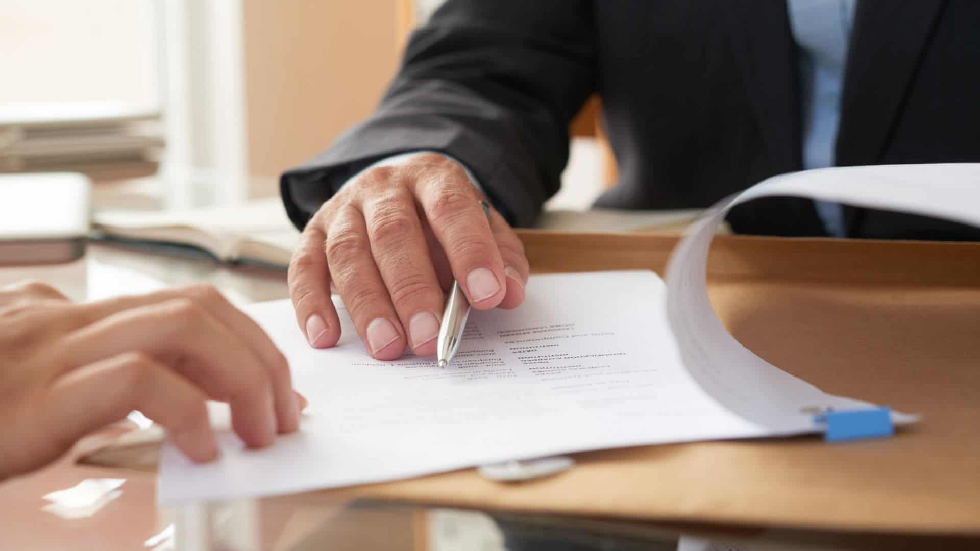 Mano di un uomo in completo che mostra documenti da firmare